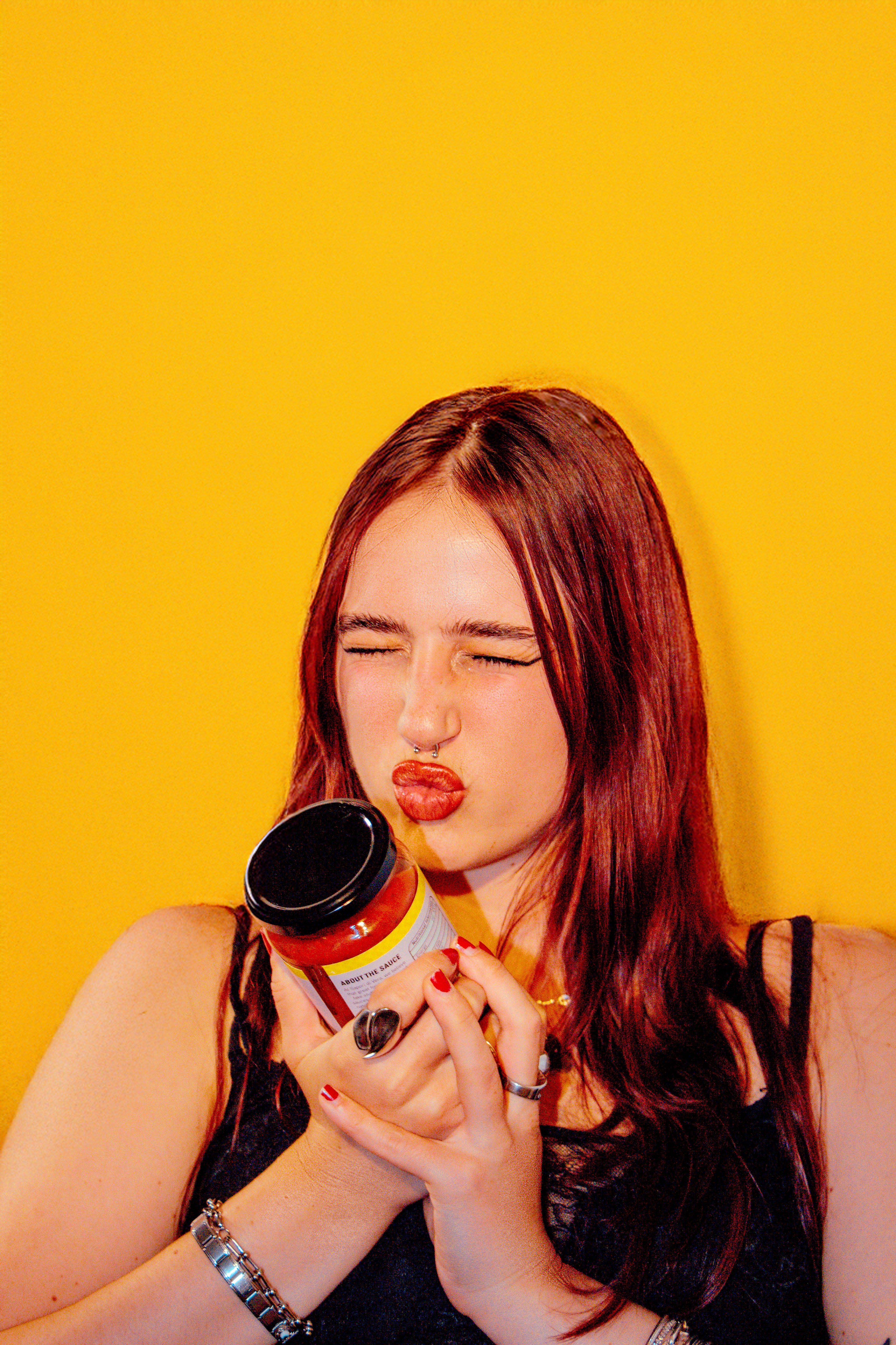 Woman holding a sapori di vera tomato jar against a yellow background